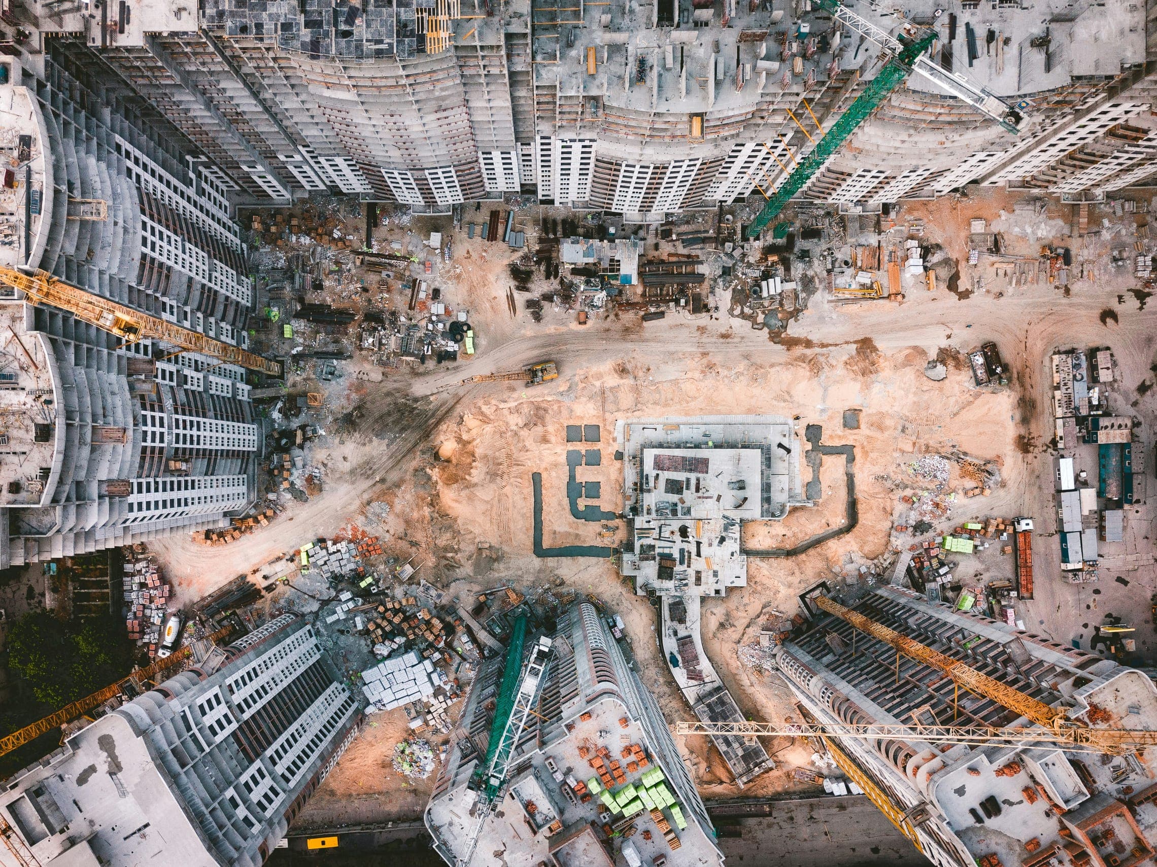 Aerial view of a large construction site with cranes, foundations and high-rise blocks under way.