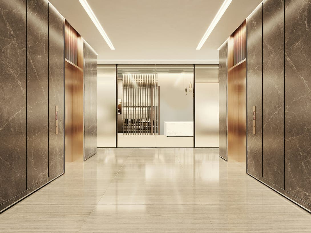 Lift lobby with dark marble walls, bronze doors and a glass entrance to a reception.