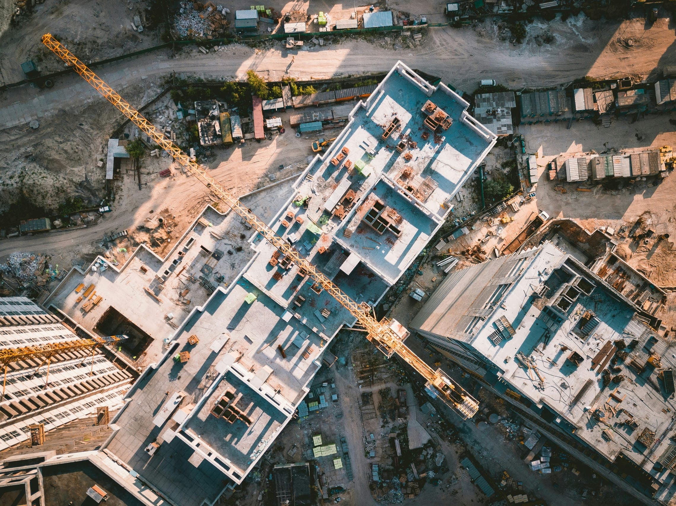 Aerial view of a construction site with concrete floors under way and a tower crane.