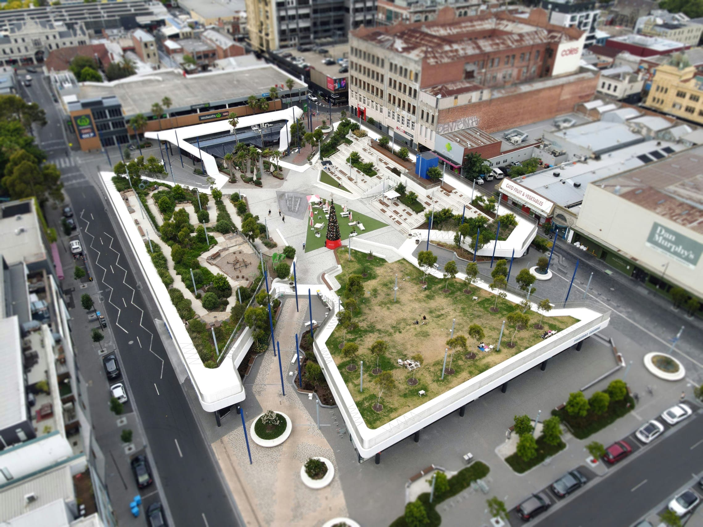 Aerial view of an elevated public park with planted beds and paths above a street.